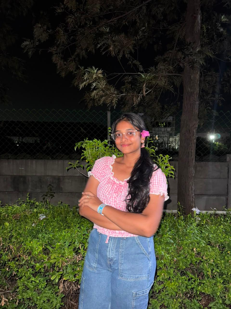Jayani Bai in a pink gingham top in a garden at night