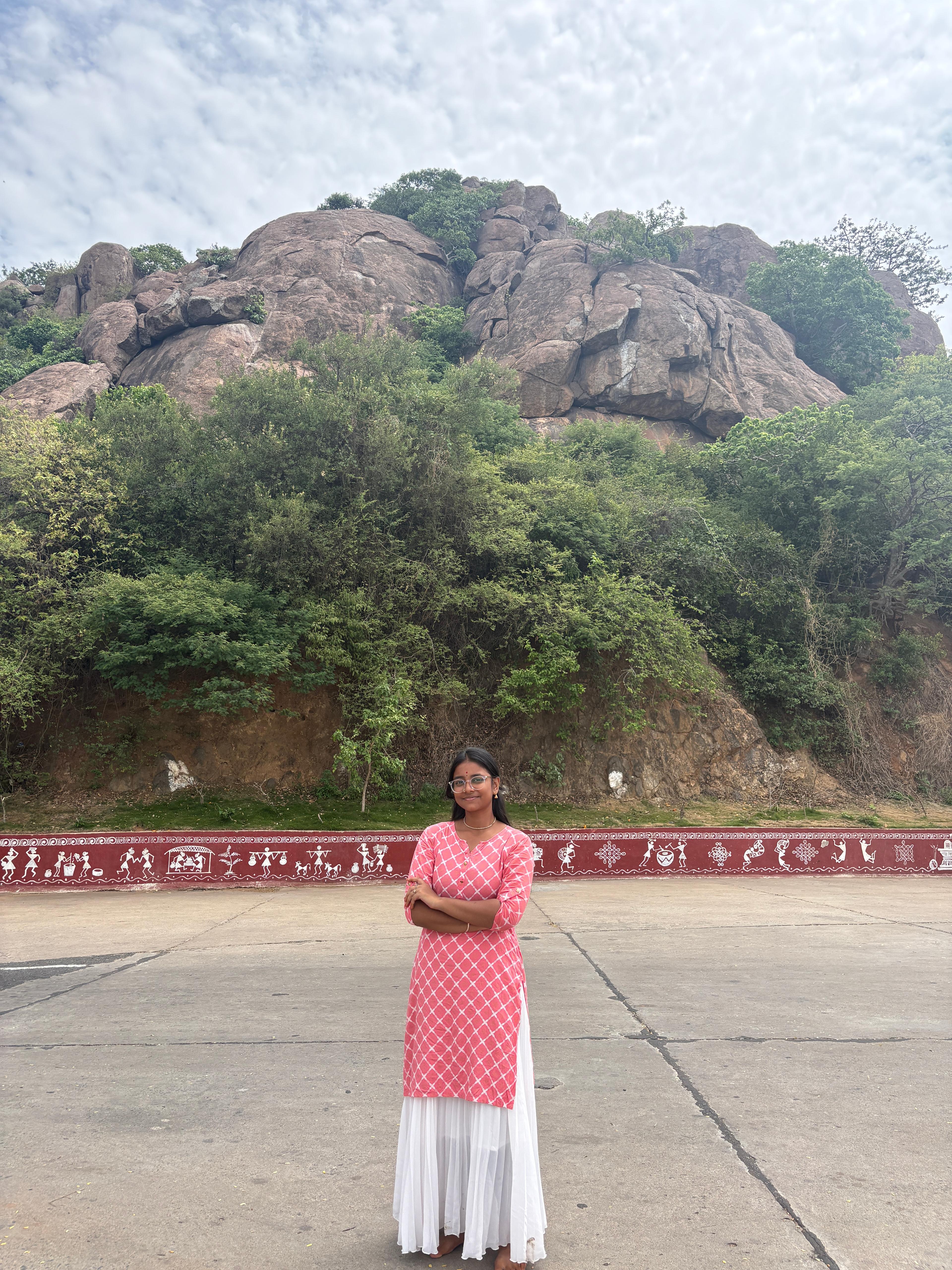 Jayani Bai in a pink dupatta outfit near rocky hills