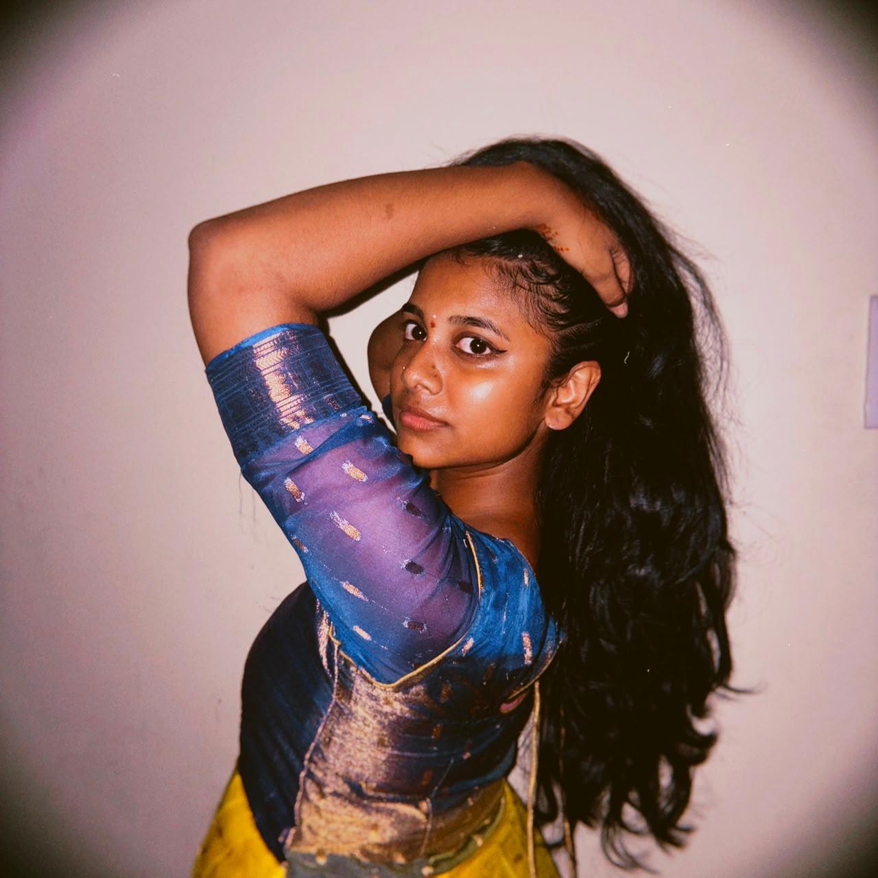 Jayani Bai in a blue and gold silk blouse, styling her hair